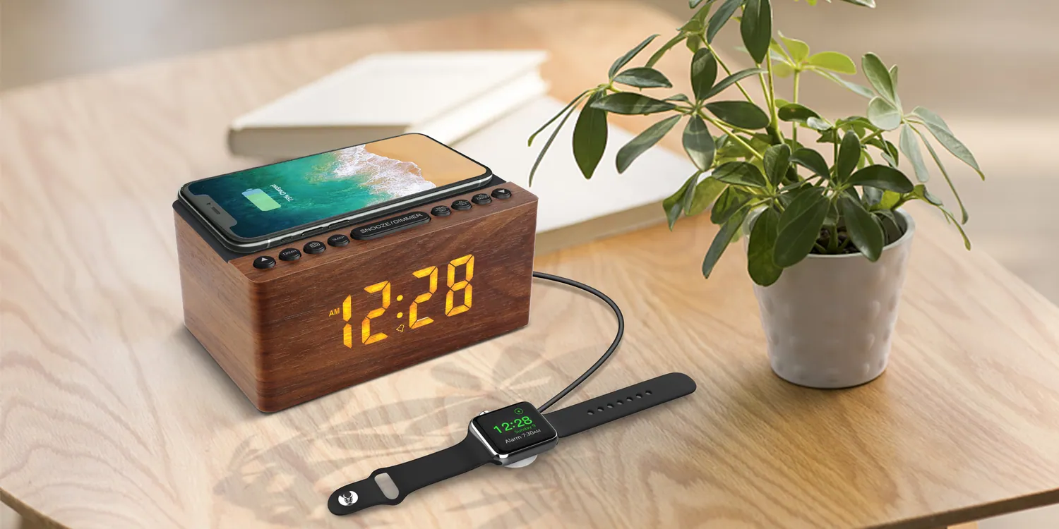 A walnut clock radio charging a phone on a desk