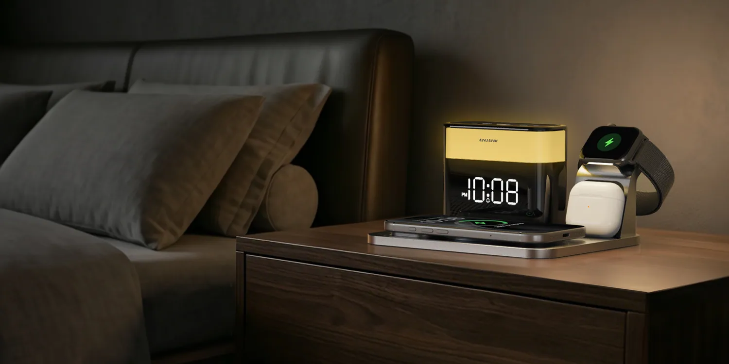 A charging dock and clock glowing on a walnut nightstand in a dark bedroom